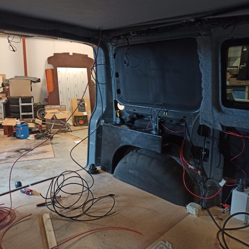 Binnenkant van de camper die helemaal gestript is en waar nu de eerste draden getrokken zijn voor de elektra van de keuken en de zonnepanelen, gezien vanuit de schuifdeur richting de achterkant