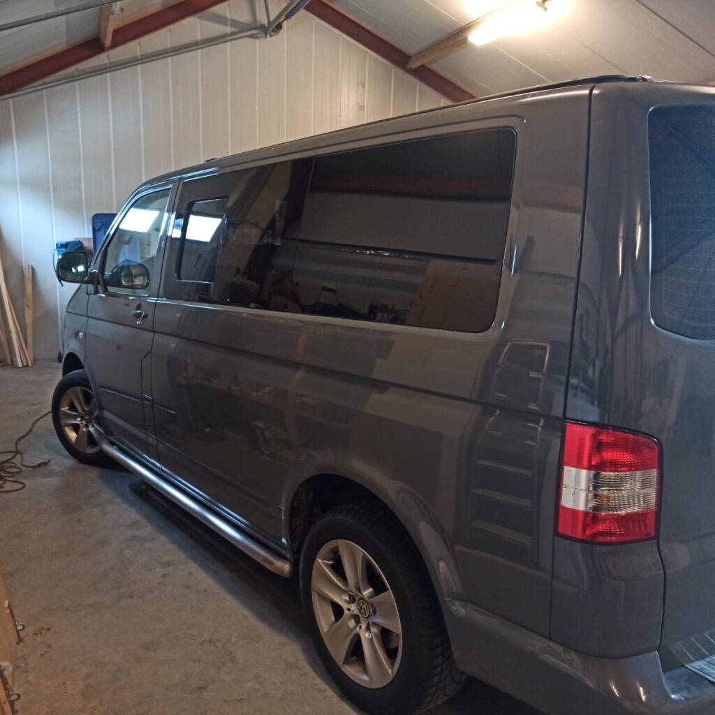 One donkergrijze Volkswagen T5 bus staat binnen bij Tiny House Campers in de loods, gezien van links achter