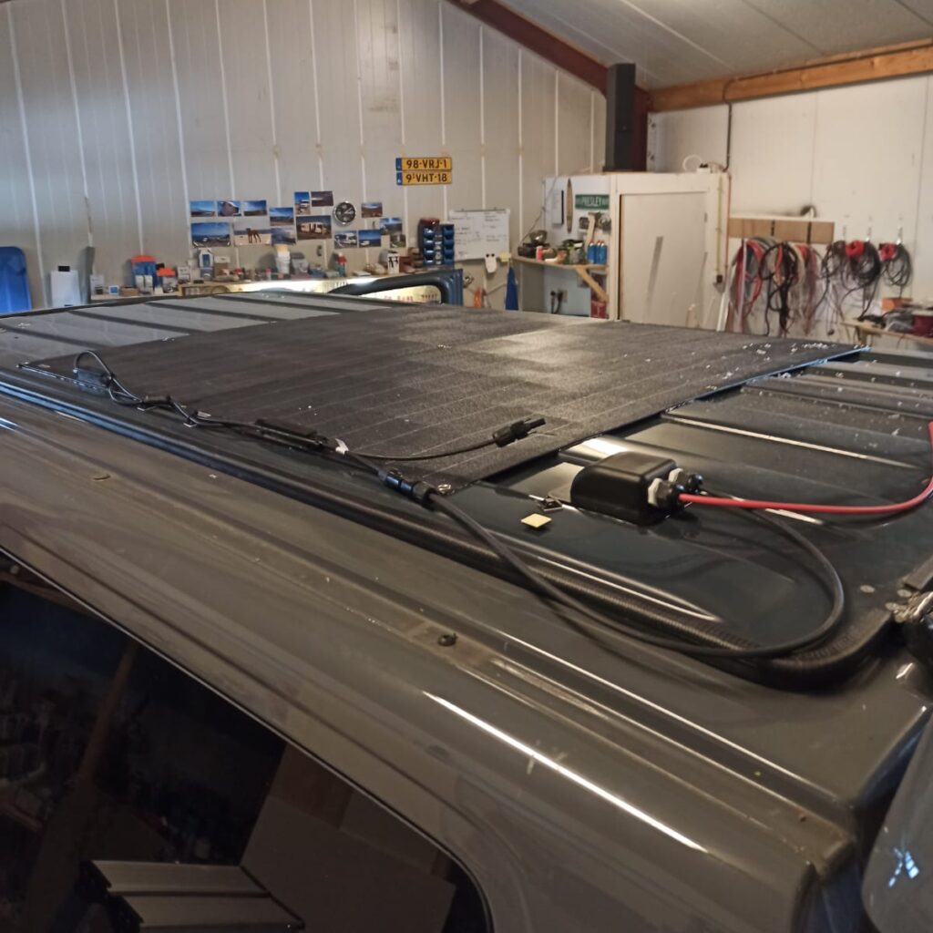 Dak van de camper, van schuin boven, met het hefdak (dicht) met dunne zonnepanelen